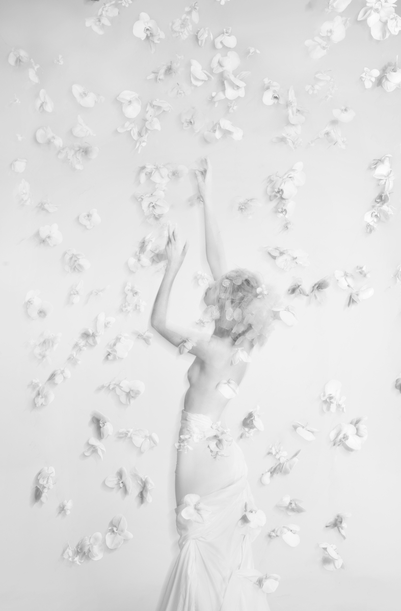 Flower installation with white floating orchids around a girl painted in white body black and white photo by Florist and set designer in Shanghai China Daria Bokova