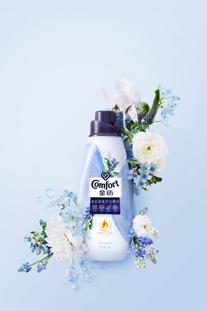 Conditioner blue bottle surrounded by white and blue flowers, sea salt